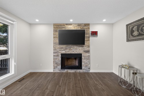 Central fireplace featuring a stacked stone surround and hearth - 15251 88A Street, Edmonton, AB - Indoor Photo Showing Living Room With Fireplace