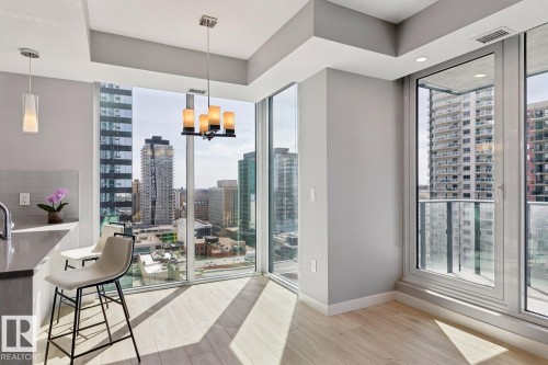 Floor-to-ceiling windows with city skyline, wood-finish flooring, recessed lighting, and a modern chandelier - #1601 10180 103 St Nw, Edmonton, AB - Indoor Photo Showing Other Room