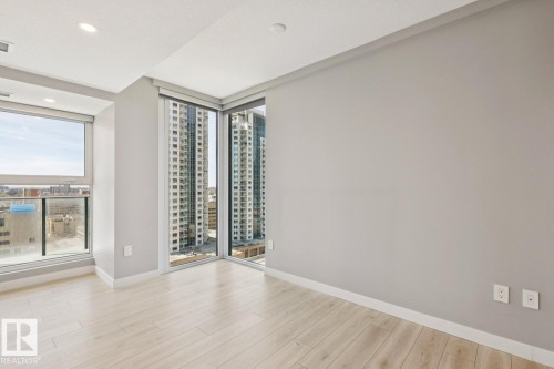 Corner room featuring expansive windows, light wood-finish flooring, recessed ceiling lighting, and neutral wall tones - #1601 10180 103 St Nw, Edmonton, AB - Indoor Photo Showing Other Room