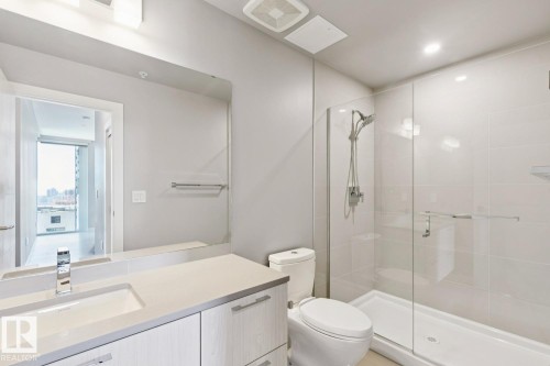 Contemporary bathroom featuring a spacious glass-enclosed shower, a vanity with an integrated sink and chrome faucet, and a large mirror - #1601 10180 103 St Nw, Edmonton, AB - Indoor Photo Showing Bathroom