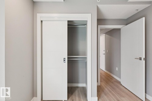 Sliding closet door with linear paneling and a dark hardware pull - #1601 10180 103 St Nw, Edmonton, AB - Indoor Photo Showing Other Room