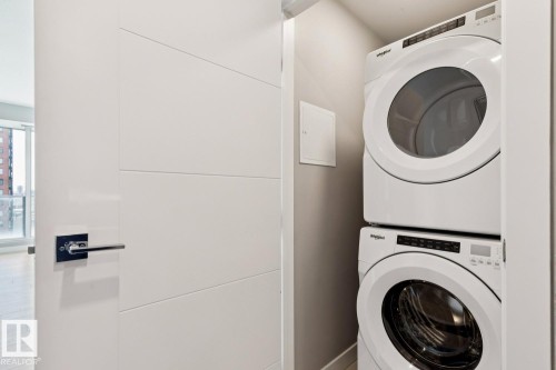 Dedicated laundry closet featuring a stacked white washer and dryer unit - #1601 10180 103 St Nw, Edmonton, AB - Indoor Photo Showing Laundry Room