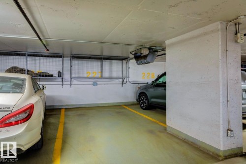 Designated parking stall within a structured garage, featuring concrete construction and overhead wire storage units - #1601 10180 103 St Nw, Edmonton, AB - Indoor Photo Showing Garage