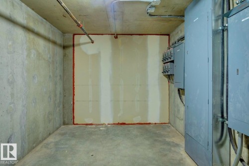 Utility space featuring concrete walls, concrete flooring, exposed overhead piping, electrical panels, and conduit - #1601 10180 103 St Nw, Edmonton, AB - Indoor