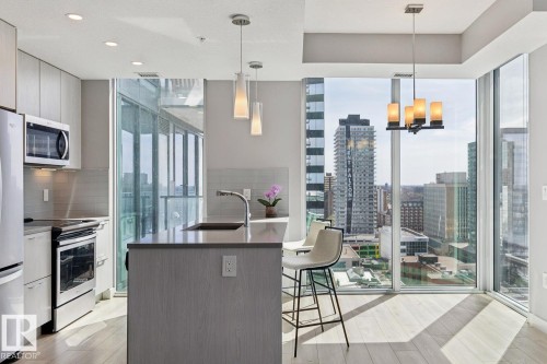 Modern kitchen featuring light wood-finish flooring and floor-to-ceiling windows - #1601 10180 103 St Nw, Edmonton, AB - Indoor Photo Showing Kitchen With Upgraded Kitchen