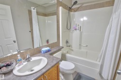 Bathroom featuring a full-size bathtub with a showerhead, a single vanity with an integrated sink, a large wall-mounted mirror, and tile backsplash - 