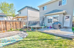 Backyard featuring a wooden privacy fence, a wooden deck, and a green lawn - 