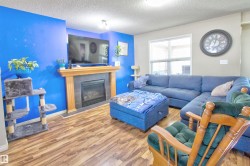 Living area featuring wood-finish flooring, a fireplace with a wood mantle and tile surround, and an expansive window with blinds - 