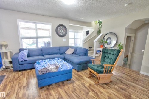 Living area featuring wood-finish flooring, neutral wall tones, and multiple windows with blinds - 14820 140 Street, Edmonton, AB - Indoor Photo Showing Living Room