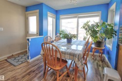 Dining area featuring wood-finish flooring, ample natural light from multiple windows, and a semi-private entry door with frosted glass - 