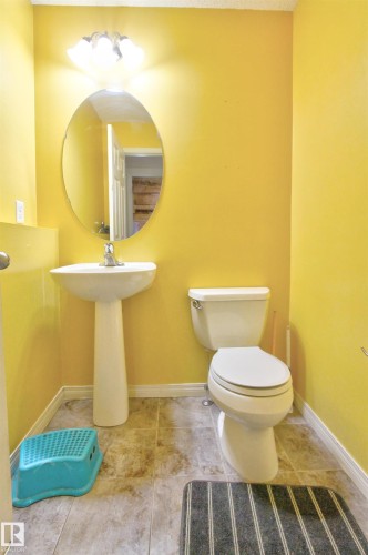 Pedestal sink with chrome faucet, oval mirror, and three-bulb vanity light fixture - 14820 140 Street, Edmonton, AB - Indoor Photo Showing Bathroom