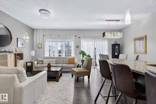 Open-concept living space featuring wood-finish flooring, a kitchen island with stone countertop, and recessed lighting - 83 Sandalwood Place, Leduc, AB - Indoor