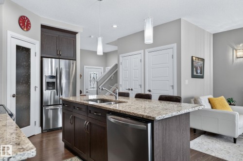 Kitchen island featuring a granite countertop, undermount sink, and integrated dishwasher - 83 Sandalwood Place, Leduc, AB - Indoor Photo Showing Kitchen With Double Sink With Upgraded Kitchen