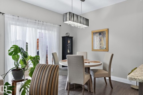 Dining area featuring wood-finish flooring, a contemporary chandelier, and light gray wall paint - 83 Sandalwood Place, Leduc, AB - Indoor Photo Showing Dining Room