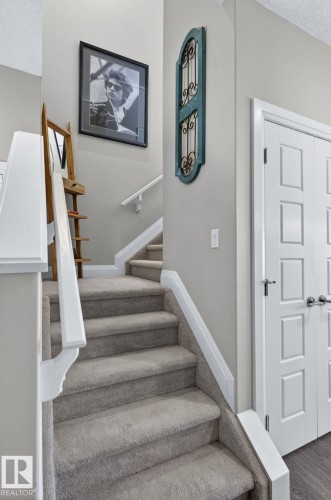 Carpeted staircase with white risers and handrails - 83 Sandalwood Place, Leduc, AB - Indoor Photo Showing Other Room
