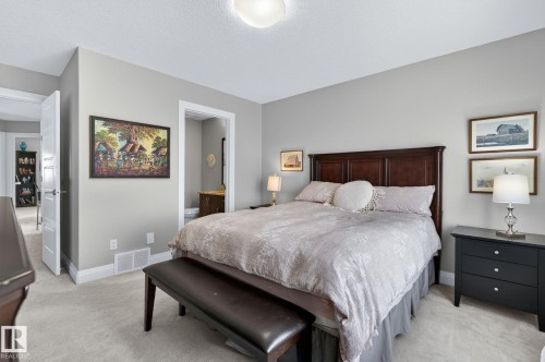 Carpeted bedroom featuring a dark wood headboard, light gray painted walls, and white trim - 83 Sandalwood Place, Leduc, AB - Indoor Photo Showing Bedroom