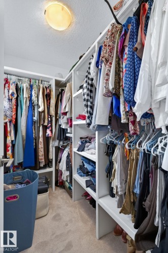 Walk-in closet featuring built-in white shelving, multiple hanging rods, and recessed lighting - 83 Sandalwood Place, Leduc, AB - Indoor With Storage