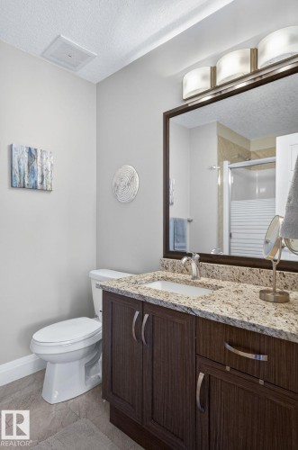 Bathroom vanity featuring a light-toned granite countertop, undermount sink, and dark wood-finish cabinetry with brushed nickel hardware - 83 Sandalwood Place, Leduc, AB - Indoor Photo Showing Bathroom