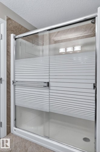 Sliding glass shower enclosure with frosted privacy banding - 83 Sandalwood Place, Leduc, AB - Indoor Photo Showing Bathroom