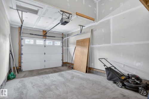 Attached garage with a white panel door and clear window inserts - 83 Sandalwood Place, Leduc, AB - Indoor Photo Showing Garage