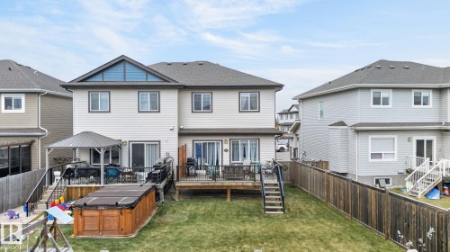 Expansive backyard featuring a tiered wooden deck, a covered patio area, and a private wooden fence - 83 Sandalwood Place, Leduc, AB - Outdoor