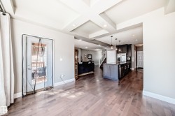 Spacious open-concept interior featuring wood-finish flooring, a kitchen island with pendant lighting, and a glass-paneled exterior door - 