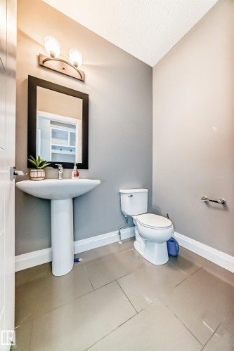 Pedestal sink with chrome faucet, complemented by an overhead two-light vanity fixture - 4155 Charles Link, Edmonton, AB - Indoor Photo Showing Bathroom