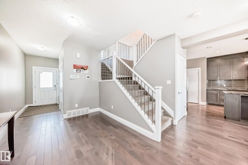 Open concept entryway featuring wood-finish flooring extending into the living spaces - 4155 Charles Link, Edmonton, AB - Indoor