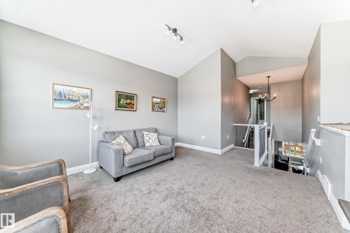 Carpeted upper level featuring vaulted ceilings, track lighting, and a prominent staircase with white railings - 4155 Charles Link, Edmonton, AB - Indoor