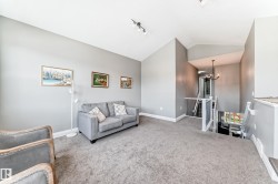 Carpeted upper level featuring vaulted ceilings, track lighting, and a prominent staircase with white railings - 