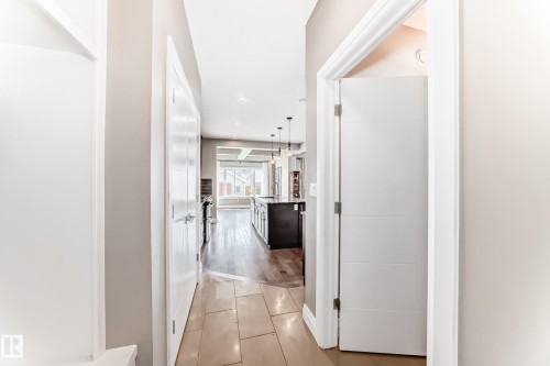 Foyer with large format tile flooring opening to hardwood flooring - 4155 Charles Link, Edmonton, AB - Indoor Photo Showing Other Room
