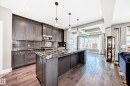 Modern kitchen featuring dark cabinetry, stone countertops, stainless steel appliances, and a tile backsplash - 4155 Charles Link, Edmonton, AB  - Indoor Photo Showing Kitchen With Upgraded Kitchen 