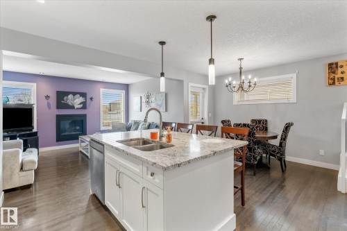 Kitchen island with double basin stainless steel sink and white cabinetry - 3 Richmond Link, Fort Saskatchewan, AB - Indoor Photo Showing Kitchen With Fireplace With Double Sink