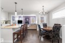 Open-concept living area featuring a kitchen island with seating, dark wood-finish flooring, white cabinetry, and a dining area with a chandelier - 3 Richmond Link, Fort Saskatchewan, AB  - Indoor Photo Showing Dining Room 