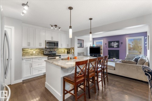 Kitchen island with pendant lighting, stone countertop, and integrated seating - 3 Richmond Link, Fort Saskatchewan, AB - Indoor Photo Showing Kitchen With Upgraded Kitchen