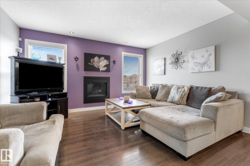 Living area featuring a floor-to-ceiling fireplace with black surround, recessed lighting, wood-finish flooring, and two windows with blinds - 3 Richmond Link, Fort Saskatchewan, AB - Indoor Photo Showing Living Room With Fireplace