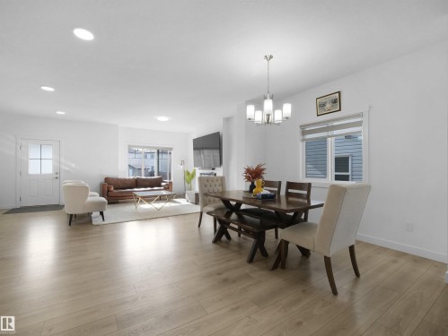 Open-concept living and dining area featuring light wood-finish flooring, recessed lighting, and a contemporary chandelier - 30 Hope Cm, Spruce Grove, AB - Indoor