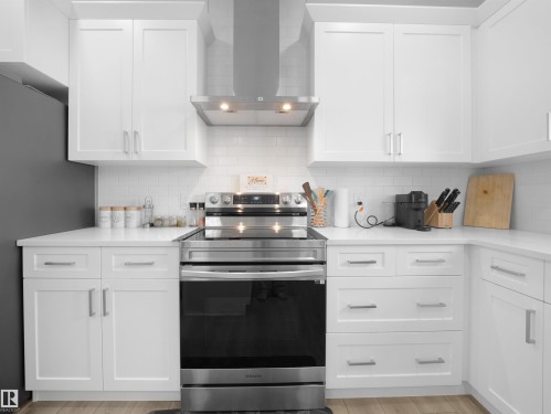 Modern kitchen featuring white shaker-style cabinetry, a stainless steel range with matching hood, subway tile backsplash, and light-toned countertops - 30 Hope Cm, Spruce Grove, AB - Indoor Photo Showing Kitchen