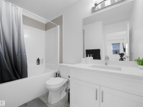 Bathroom featuring a white vanity with an integrated sink, chrome faucet, and rectangular mirror - 30 Hope Cm, Spruce Grove, AB - Indoor Photo Showing Bathroom