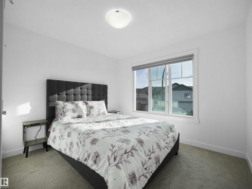 Bedroom featuring a large window, neutral wall paint, and light-colored carpet flooring - 30 Hope Cm, Spruce Grove, AB - Indoor Photo Showing Bedroom