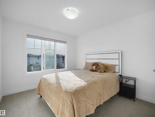 Light-filled interior featuring a large multi-pane window, white trim, recessed carpet flooring, and a flush mount ceiling light fixture - 30 Hope Cm, Spruce Grove, AB - Indoor Photo Showing Bedroom