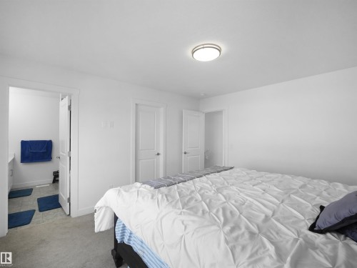 Neutral tone bedroom featuring a flush mount ceiling light, white walls, and light-colored carpeting - 30 Hope Cm, Spruce Grove, AB - Indoor Photo Showing Bedroom
