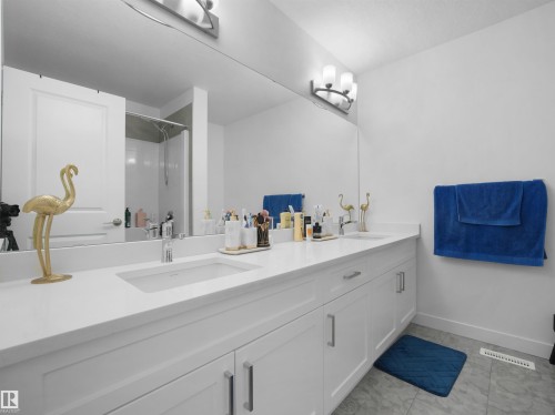 Double vanity with an integrated rectangular sink, white countertop, and white cabinetry featuring brushed nickel hardware - 30 Hope Cm, Spruce Grove, AB - Indoor Photo Showing Bathroom