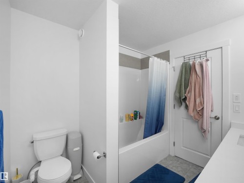Bathroom featuring a white bathtub with a shower, a commode, and a white vanity with a rectangular sink - 30 Hope Cm, Spruce Grove, AB - Indoor Photo Showing Bathroom