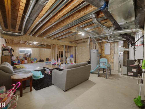 Spacious unfinished basement with exposed wooden joists and ductwork, featuring a concrete floor, an egress window, and visible utility systems - 30 Hope Cm, Spruce Grove, AB - Indoor Photo Showing Basement