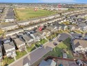 Aerial view of a residential neighborhood with detached homes, featuring street parking, a central green space, and visible community buildings - 30 Hope Cm, Spruce Grove, AB  - Outdoor With View 