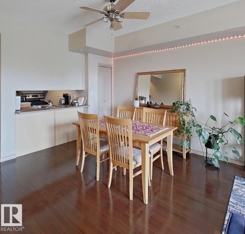 Open-concept living space featuring wood-finish flooring, a kitchen pass-through, and a ceiling fan - 707 10319 111 Street Nw, Edmonton, AB - Indoor Photo Showing Dining Room