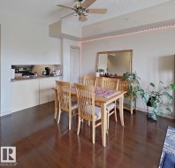 Open-concept living space featuring wood-finish flooring, a kitchen pass-through, and a ceiling fan - 