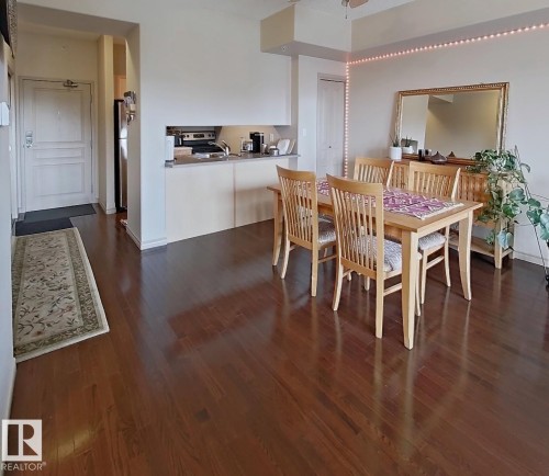 Rich wood-finish flooring throughout the dining area and entry - 707 10319 111 Street Nw, Edmonton, AB - Indoor Photo Showing Dining Room