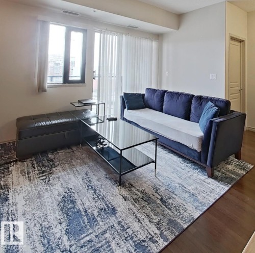 Living area with wood-finish flooring, white walls, and a large window - 707 10319 111 Street Nw, Edmonton, AB - Indoor Photo Showing Living Room